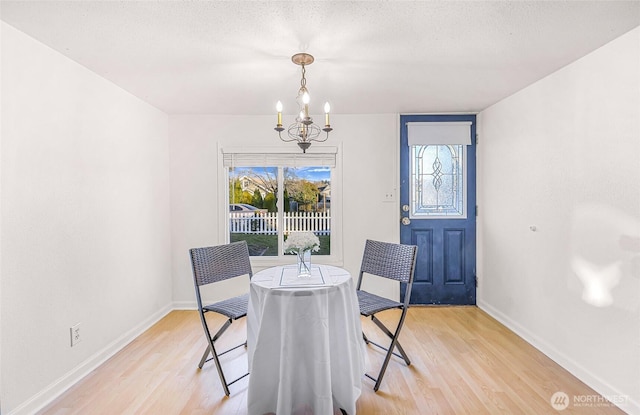 dining room with a notable chandelier, a textured ceiling, and light wood-style floors