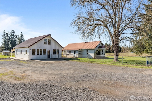 modern farmhouse featuring metal roof, driveway, and fence