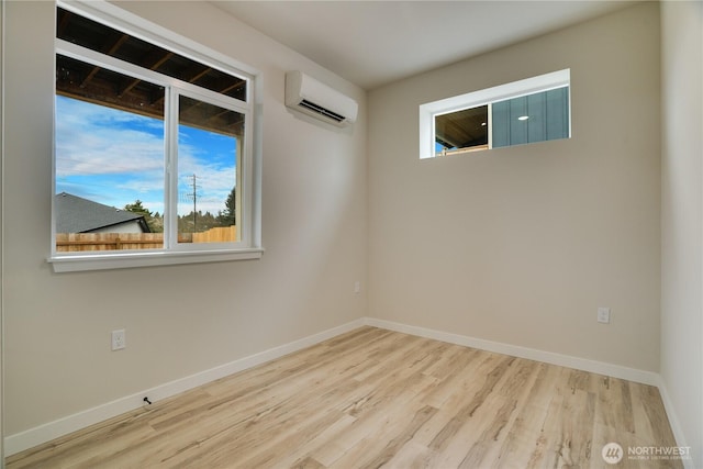 unfurnished room featuring baseboards, a wall unit AC, and wood finished floors