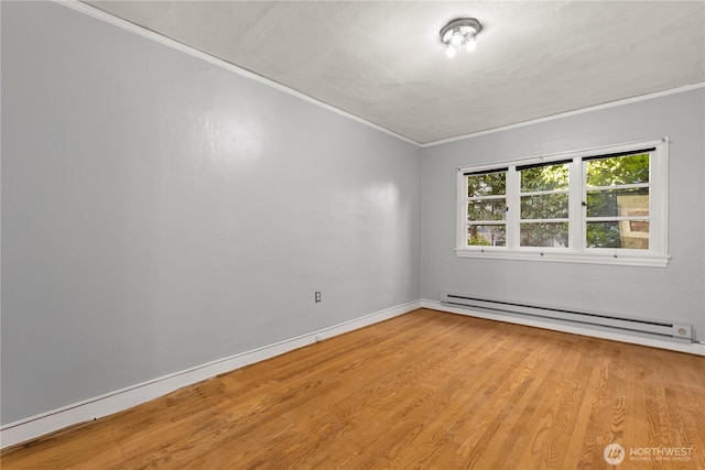 empty room featuring ornamental molding, baseboards, baseboard heating, and wood finished floors