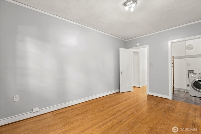 unfurnished bedroom featuring ornamental molding, wood finished floors, washer / dryer, and baseboards