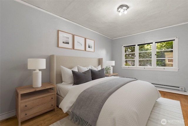 bedroom featuring baseboard heating, crown molding, and wood finished floors