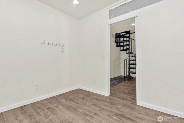 spare room featuring stairway, baseboards, and wood finished floors