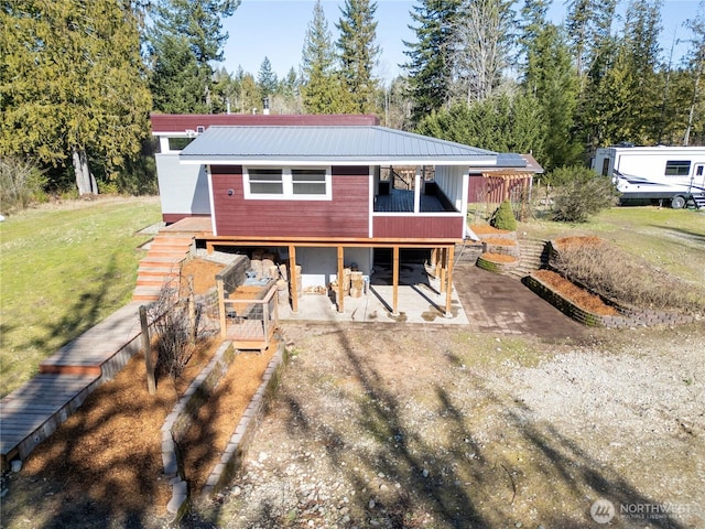 back of property featuring a deck, metal roof, a yard, and driveway