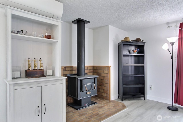 details with baseboards, a textured ceiling, wood finished floors, and a wood stove