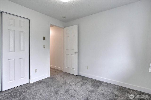 unfurnished bedroom with carpet flooring, baseboards, and a textured ceiling