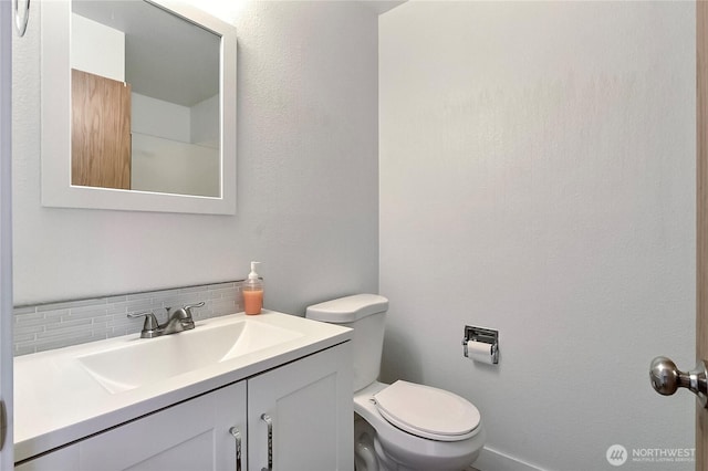 bathroom featuring backsplash, toilet, and vanity