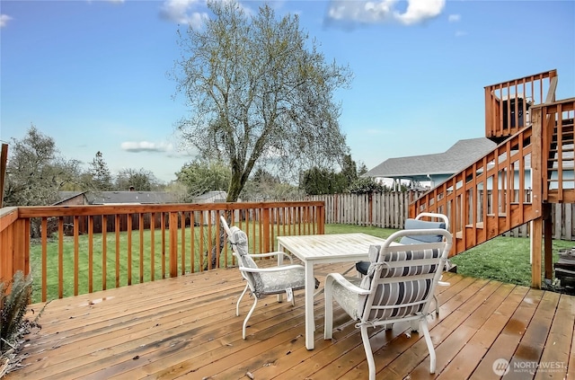 wooden deck featuring a yard, outdoor dining area, stairway, and fence