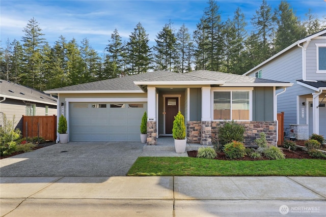 view of front of house with board and batten siding, fence, a garage, stone siding, and driveway