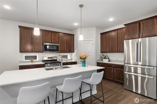 kitchen featuring stainless steel appliances, dark wood finished floors, dark brown cabinetry, and a kitchen breakfast bar