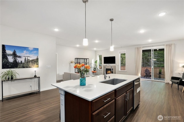 kitchen with dark wood-style flooring, light countertops, open floor plan, a sink, and a lit fireplace