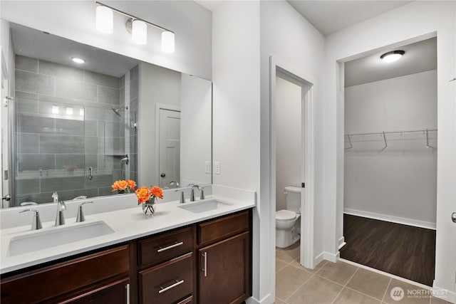 full bath featuring tile patterned flooring, a sink, a shower stall, and toilet