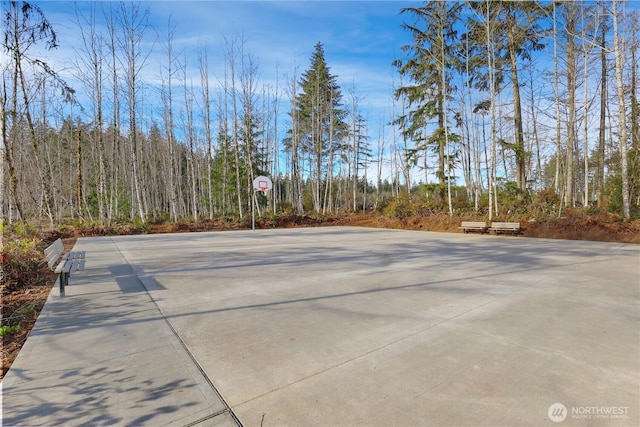 view of sport court featuring community basketball court and a forest view