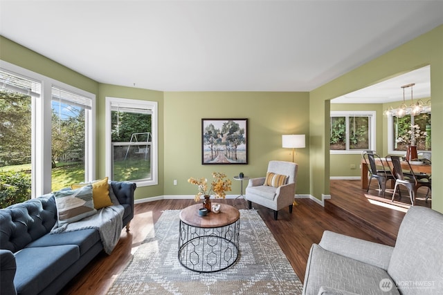 living area featuring baseboards, a chandelier, and wood finished floors