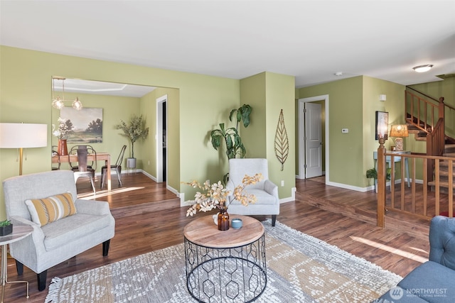 living room featuring stairway, baseboards, and wood finished floors