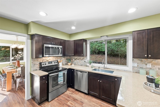 kitchen with stainless steel appliances, a wealth of natural light, light countertops, a sink, and dark brown cabinetry