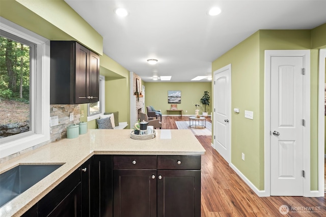 kitchen with baseboards, open floor plan, wood finished floors, a peninsula, and backsplash