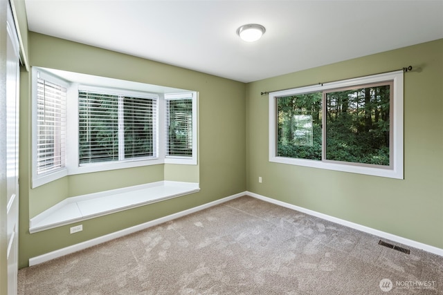 unfurnished room featuring carpet, visible vents, and a healthy amount of sunlight