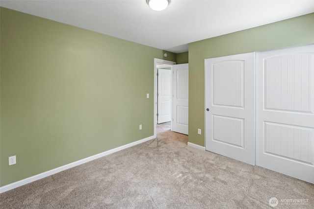 unfurnished bedroom featuring carpet, baseboards, and a closet