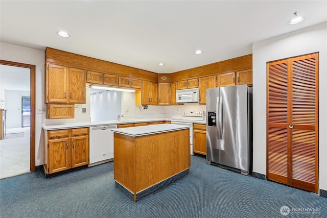 kitchen with brown cabinetry, a center island, white appliances, and light countertops