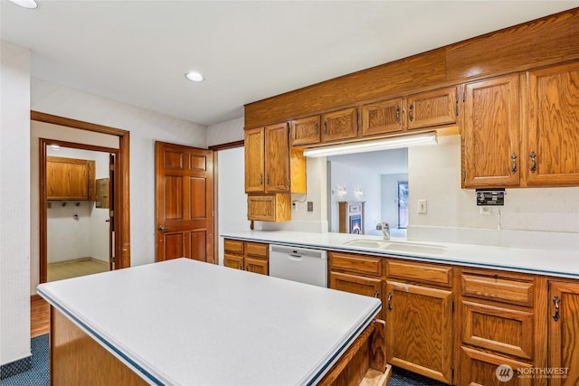 kitchen with a sink, brown cabinetry, light countertops, and dishwasher