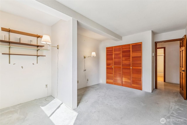 unfurnished bedroom featuring carpet floors, a closet, and beam ceiling