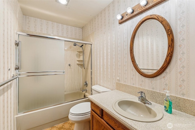 full bathroom featuring toilet, wallpapered walls, shower / bath combination with glass door, and vanity