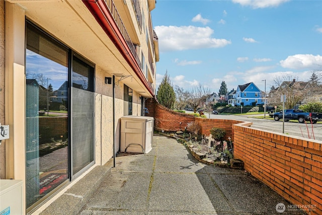 view of property exterior featuring stucco siding, a residential view, fence, and a patio