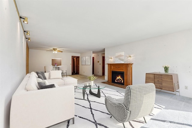 living room with a fireplace with flush hearth, light carpet, and ceiling fan