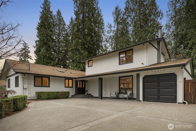 view of front of house with an attached garage, fence, and driveway