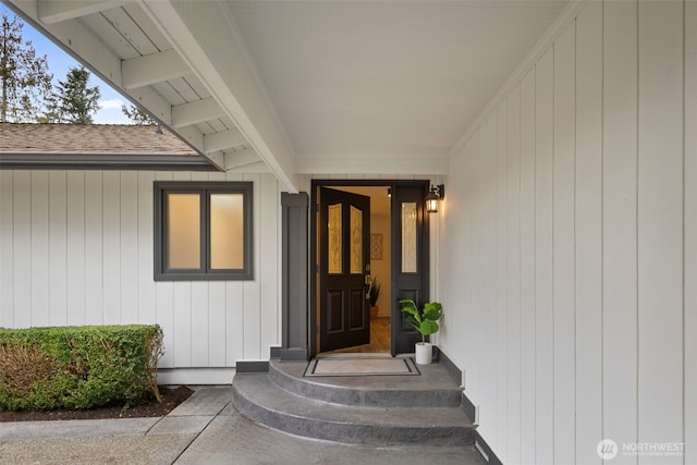 view of exterior entry with a shingled roof