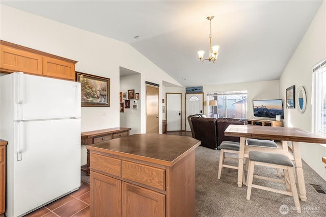 kitchen featuring a kitchen island, lofted ceiling, an inviting chandelier, freestanding refrigerator, and dark countertops