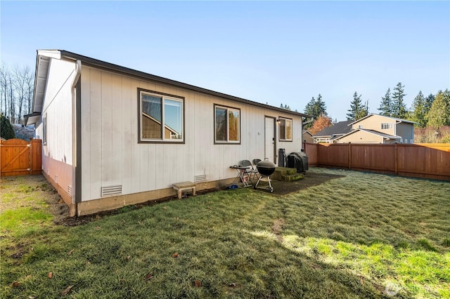 rear view of house featuring a fenced backyard, a lawn, and crawl space