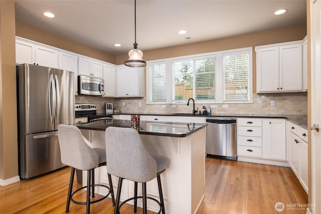 kitchen with light wood-style flooring, a kitchen bar, stainless steel appliances, and a sink