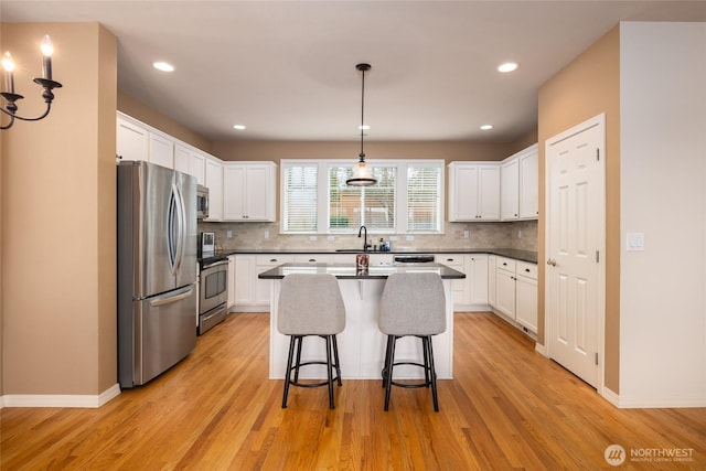 kitchen featuring appliances with stainless steel finishes, an island with sink, a sink, and white cabinets