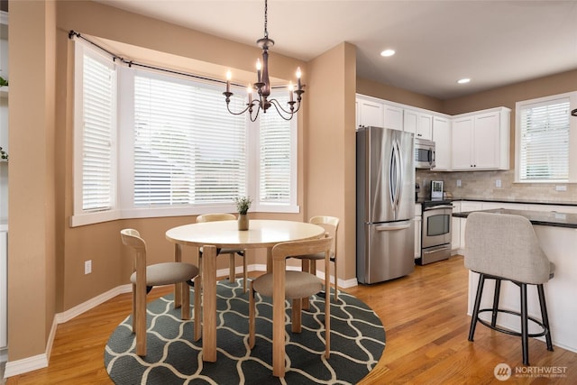 dining space with light wood-style floors, recessed lighting, a notable chandelier, and baseboards