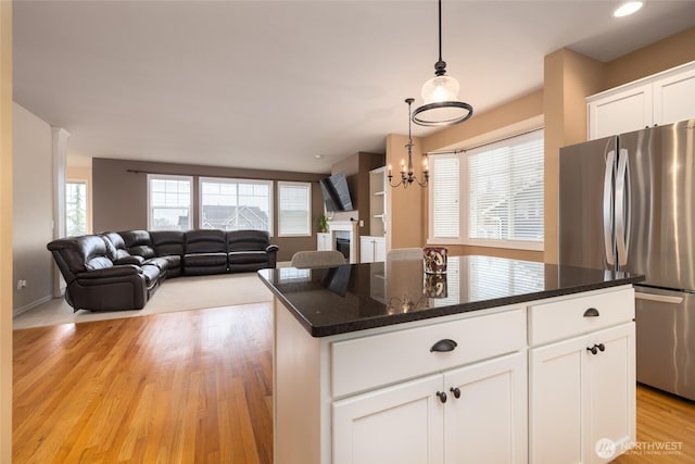 kitchen with dark stone countertops, freestanding refrigerator, light wood-style floors, white cabinetry, and pendant lighting