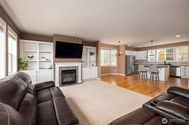 living room featuring light wood-type flooring, recessed lighting, a wealth of natural light, and a tile fireplace