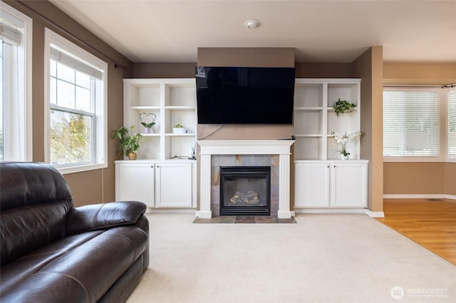 carpeted living room featuring a tiled fireplace, wood finished floors, and baseboards