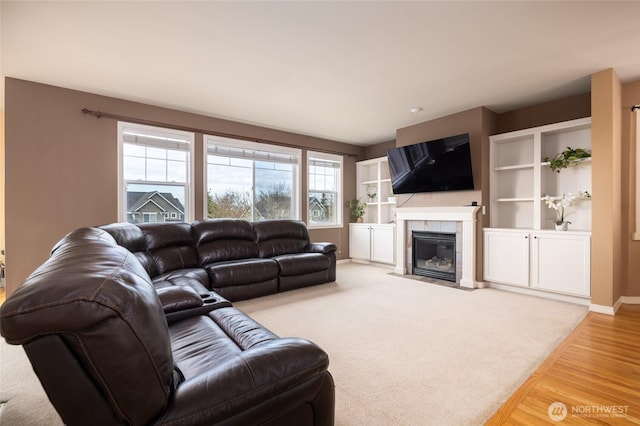 living room with light wood finished floors, a tiled fireplace, and baseboards