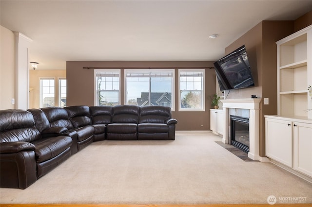 living area with a wealth of natural light, light carpet, and a tiled fireplace