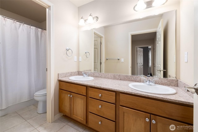 bathroom with double vanity, tile patterned flooring, a sink, and toilet