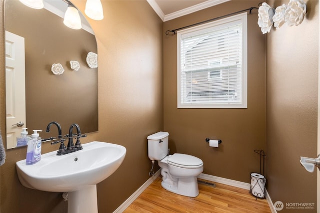 bathroom featuring toilet, wood finished floors, visible vents, baseboards, and crown molding