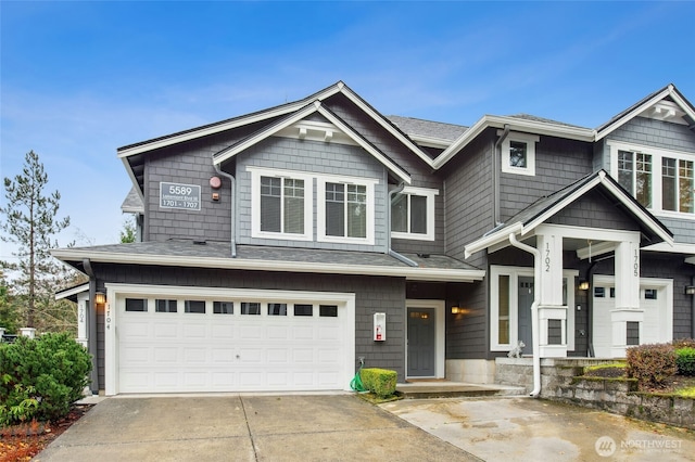 view of front facade with a shingled roof, concrete driveway, and an attached garage