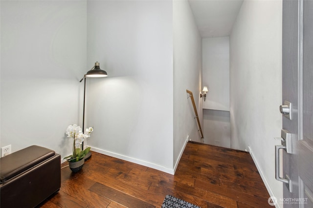 interior space featuring wood-type flooring, baseboards, and an upstairs landing