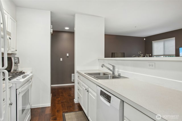 kitchen with white appliances, white cabinets, dark wood finished floors, light countertops, and a sink