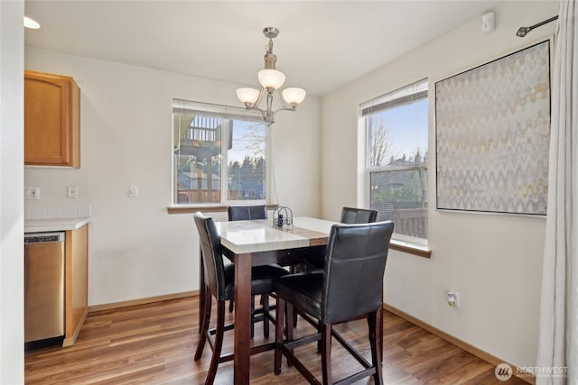 dining space with light wood-style floors, baseboards, and an inviting chandelier