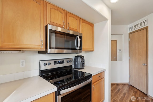 kitchen with appliances with stainless steel finishes, light countertops, and wood finished floors