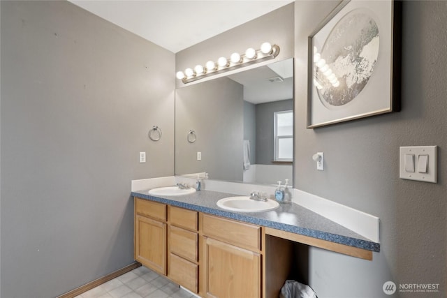 bathroom with visible vents, a sink, baseboards, and double vanity