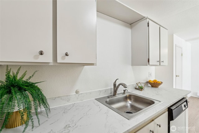 kitchen with dishwasher, white cabinets, and a sink